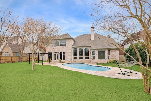 rear view of property with a fenced in pool, a patio area, and a lawn