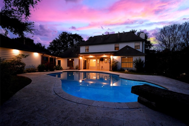 pool at dusk with a patio area