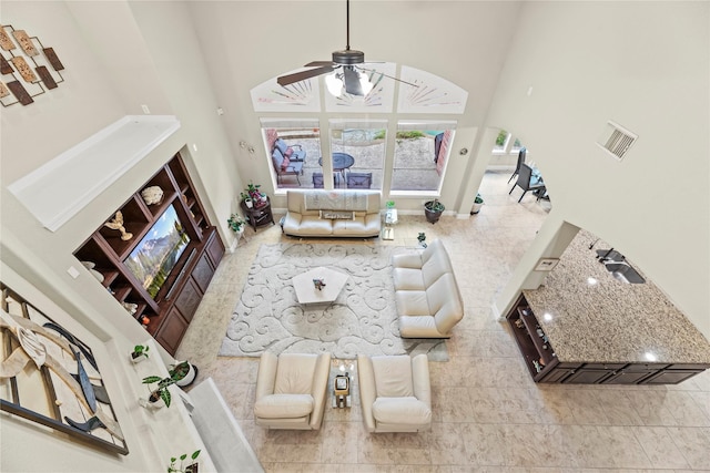 living room with ceiling fan and a towering ceiling