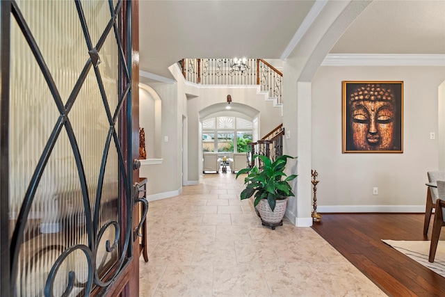 entrance foyer featuring hardwood / wood-style floors, crown molding, and a notable chandelier