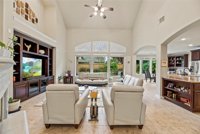 living room with ceiling fan, a high end fireplace, a towering ceiling, and sink