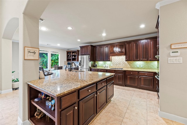 kitchen with light stone countertops, dark brown cabinetry, appliances with stainless steel finishes, sink, and ornamental molding