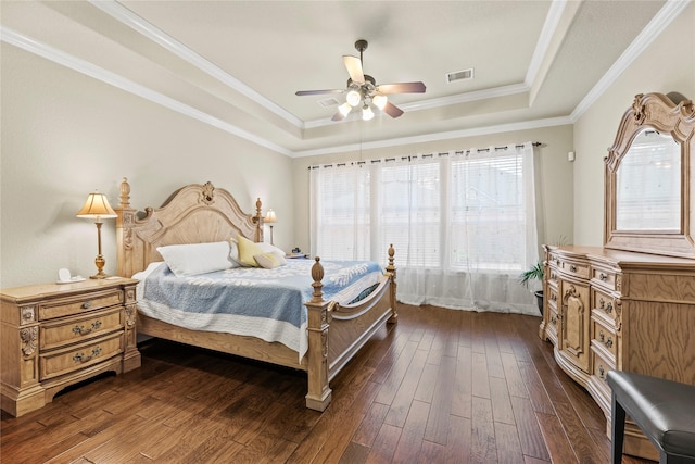 bedroom with ceiling fan, dark hardwood / wood-style flooring, crown molding, and a tray ceiling