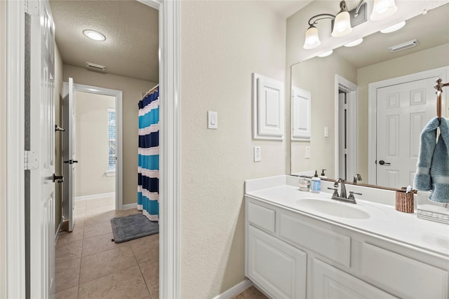 bathroom with a textured ceiling, vanity, and tile patterned flooring