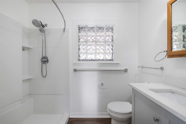 bathroom featuring toilet, vanity, and a shower