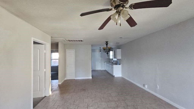 empty room with ceiling fan with notable chandelier