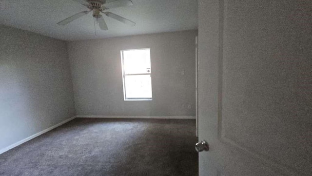 empty room featuring ceiling fan and dark carpet