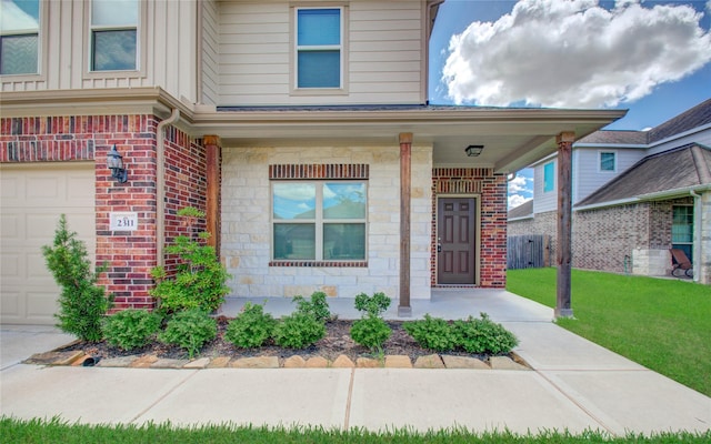 doorway to property featuring covered porch, a garage, and a yard