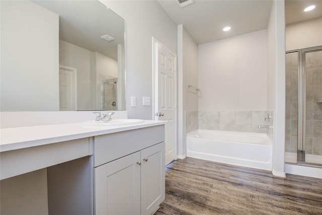 bathroom with hardwood / wood-style flooring, vanity, and plus walk in shower