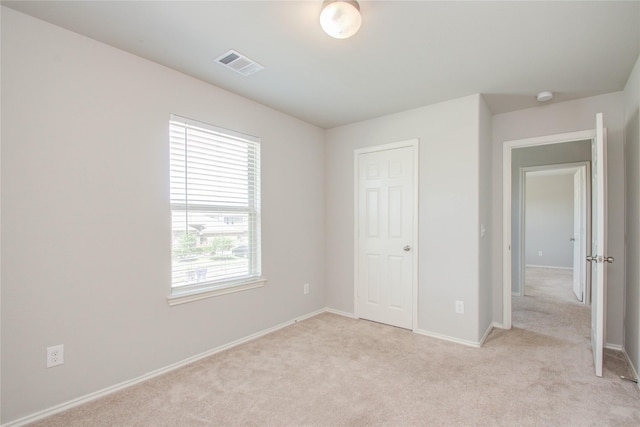 unfurnished bedroom featuring light carpet and a closet