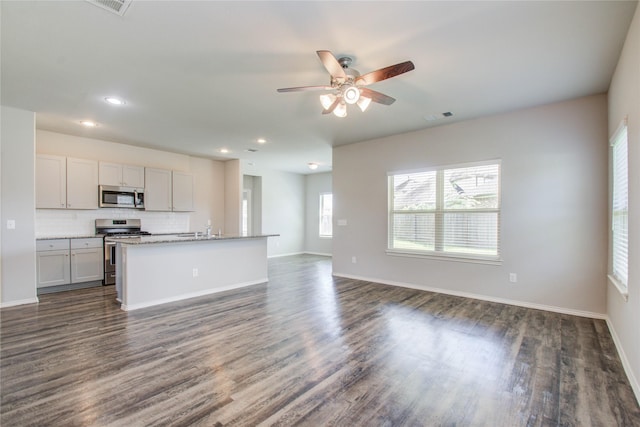 kitchen with decorative backsplash, dark hardwood / wood-style floors, an island with sink, and stainless steel appliances