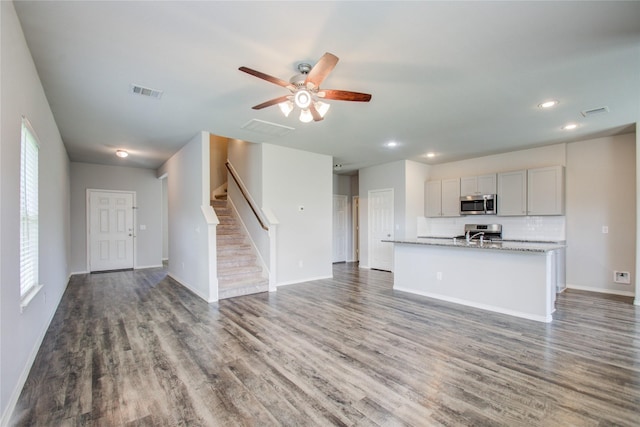 interior space with ceiling fan, a wealth of natural light, and dark hardwood / wood-style flooring