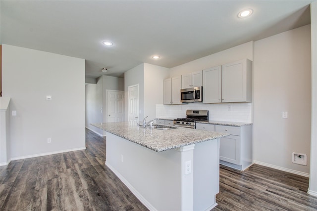 kitchen featuring decorative backsplash, sink, a kitchen island with sink, dark wood-type flooring, and stainless steel appliances