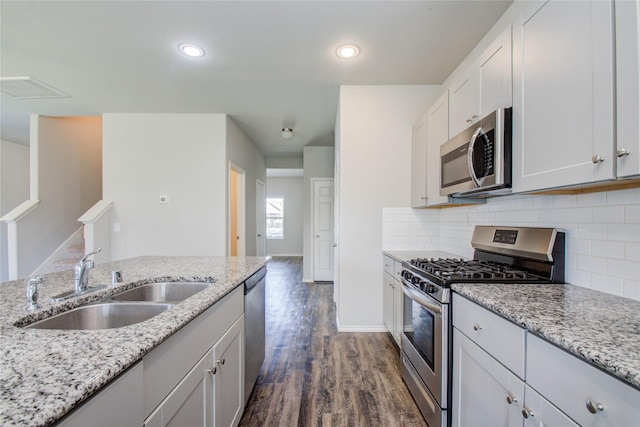 kitchen with light stone countertops, stainless steel appliances, decorative backsplash, and sink