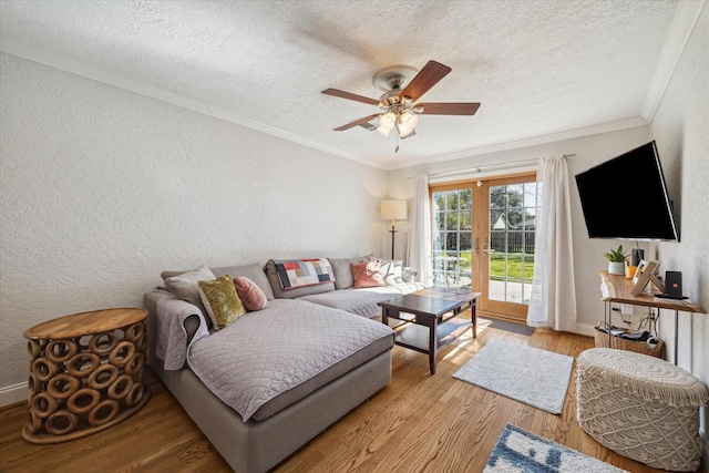 living room featuring ceiling fan, crown molding, light hardwood / wood-style floors, and french doors