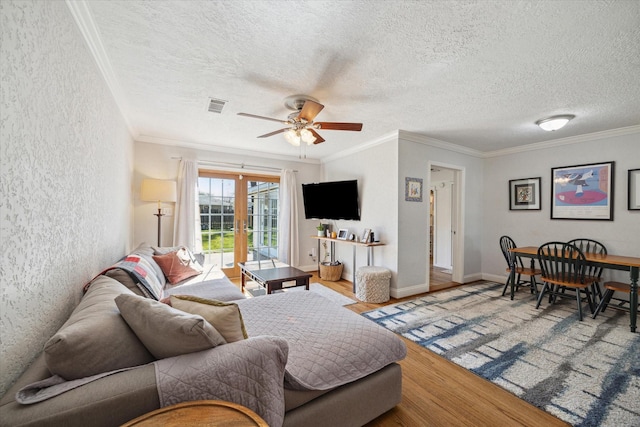 living room with hardwood / wood-style flooring, french doors, ornamental molding, and ceiling fan