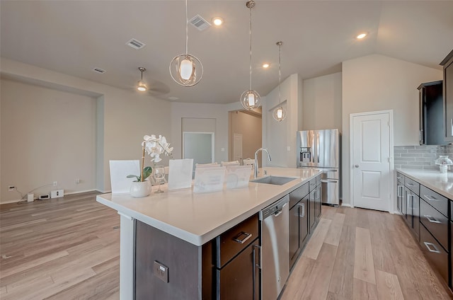 kitchen with a center island with sink, stainless steel appliances, tasteful backsplash, pendant lighting, and sink