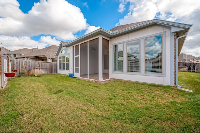 back of house featuring a lawn and a sunroom