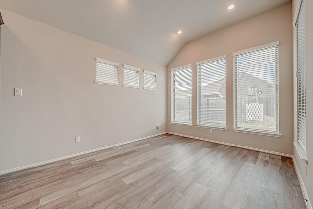 spare room featuring a wealth of natural light, light hardwood / wood-style flooring, and vaulted ceiling