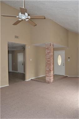 unfurnished living room with ornate columns, carpet floors, and ceiling fan