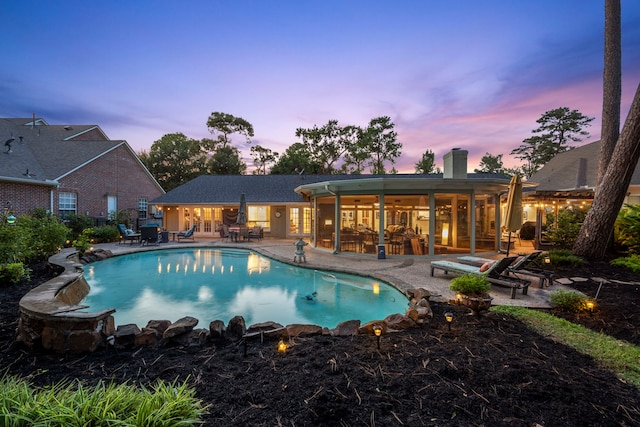 pool at dusk with a patio area