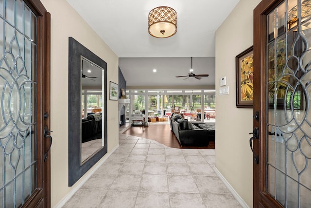 foyer featuring ceiling fan, plenty of natural light, light tile patterned floors, and lofted ceiling