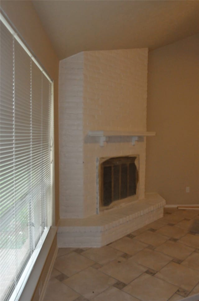 unfurnished living room with tile patterned flooring and a brick fireplace