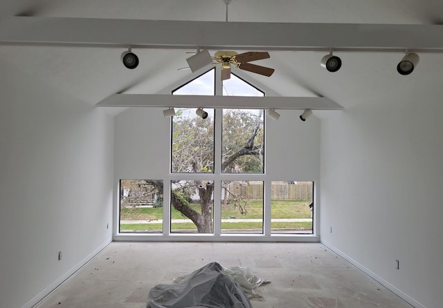 unfurnished living room featuring ceiling fan, vaulted ceiling with beams, a healthy amount of sunlight, and rail lighting