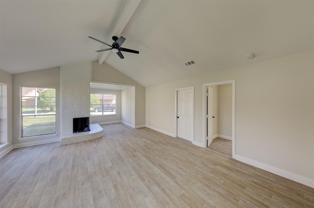 unfurnished living room with ceiling fan, lofted ceiling with beams, a fireplace, and light hardwood / wood-style flooring