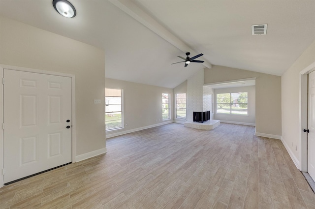 unfurnished living room featuring light wood-type flooring, ceiling fan, a fireplace, and lofted ceiling with beams