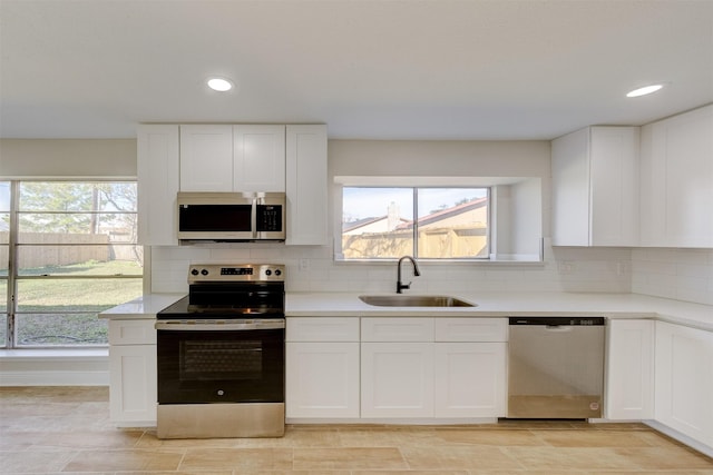 kitchen with backsplash, sink, white cabinets, and appliances with stainless steel finishes