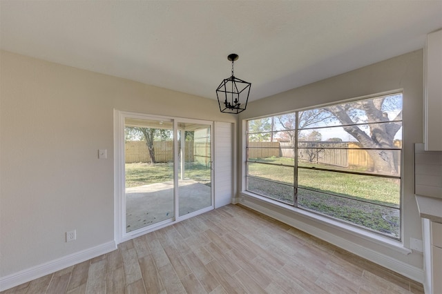 unfurnished dining area with light hardwood / wood-style floors and a notable chandelier