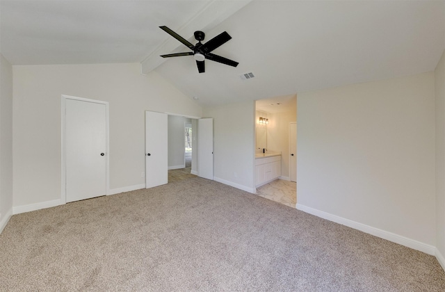 unfurnished bedroom featuring light carpet, ceiling fan, ensuite bathroom, and lofted ceiling with beams