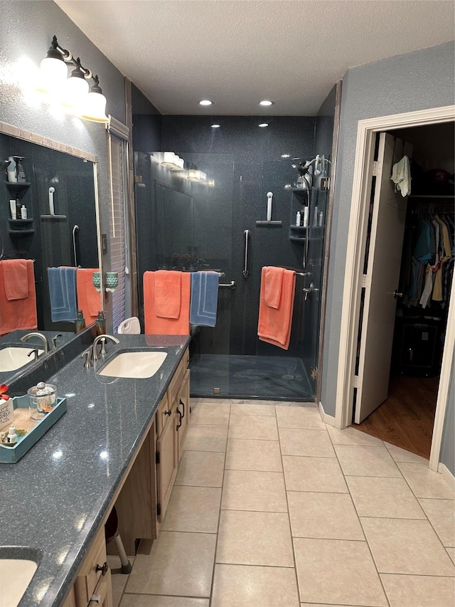 bathroom featuring a shower with shower door, a textured ceiling, vanity, and tile patterned flooring