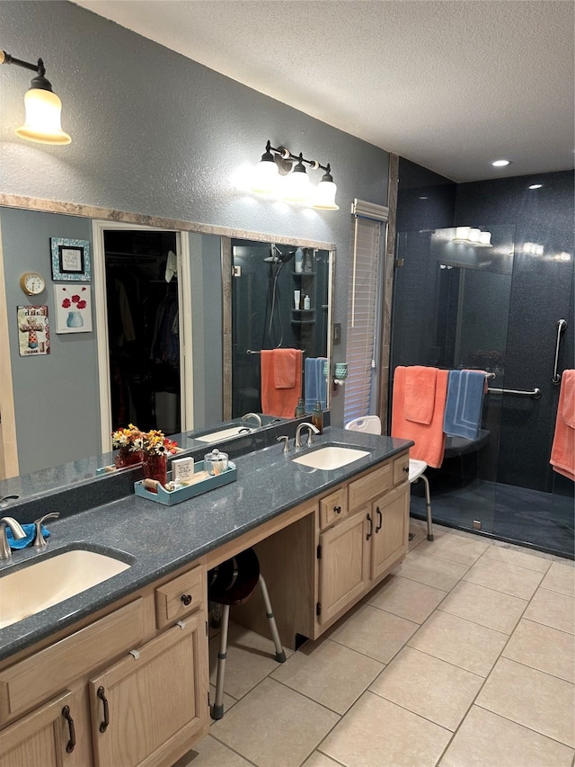 bathroom with a textured ceiling, a shower with door, vanity, and tile patterned flooring