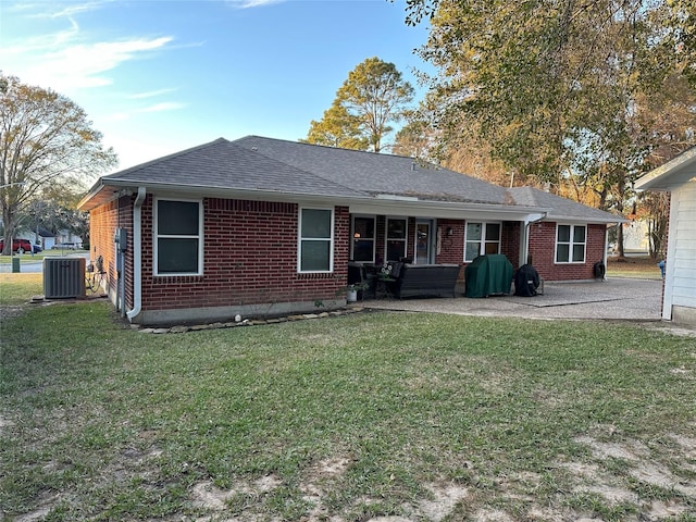 rear view of house featuring cooling unit, a lawn, and a patio