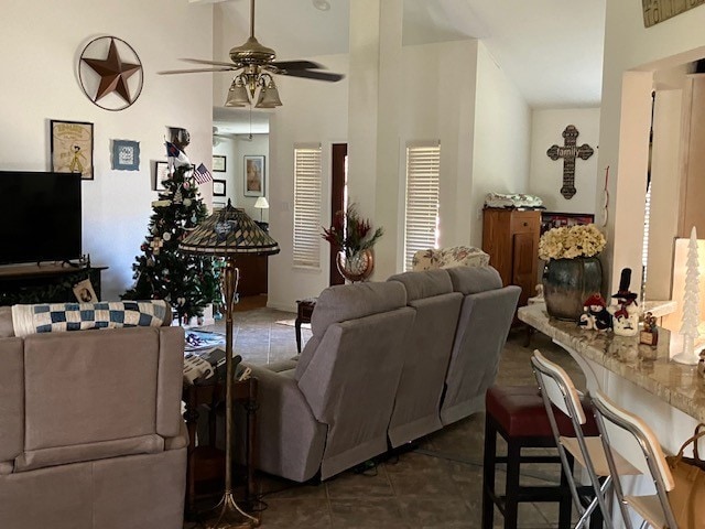 living room with ceiling fan and dark tile patterned flooring