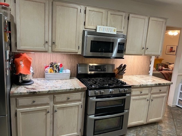 kitchen with light stone counters, stainless steel appliances, and tasteful backsplash