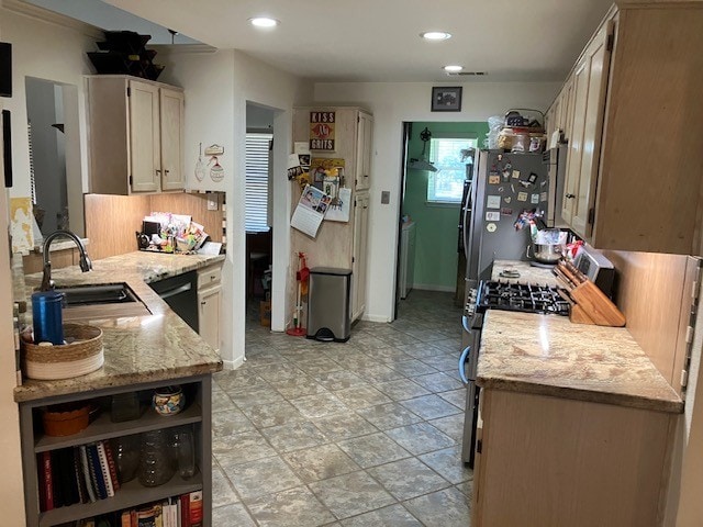 kitchen with kitchen peninsula, appliances with stainless steel finishes, backsplash, light stone countertops, and sink