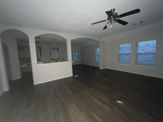 unfurnished living room featuring dark wood-type flooring and ceiling fan