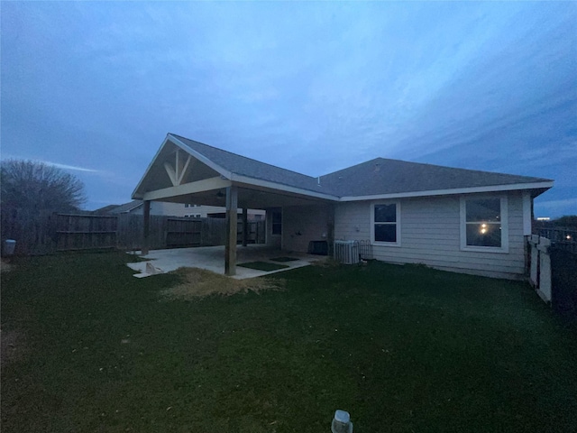 back house at dusk featuring a patio and a yard