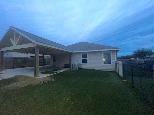 back house at dusk with a yard, a patio area, and central AC