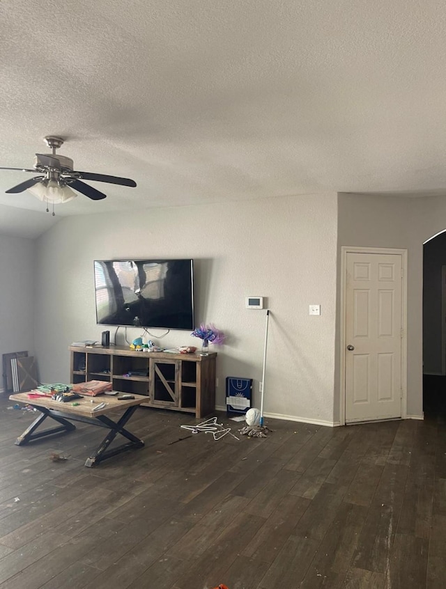 living room featuring dark wood-type flooring, ceiling fan, and a textured ceiling