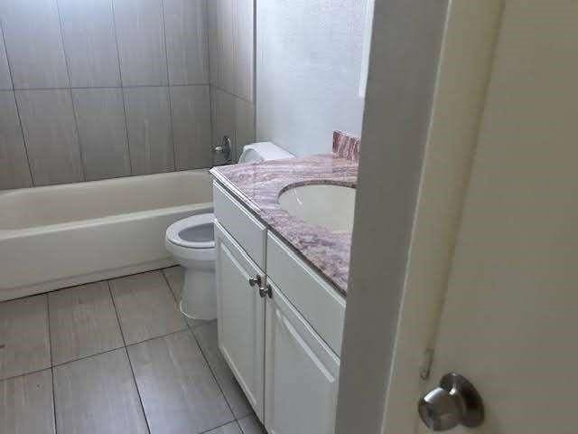 full bathroom featuring toilet, vanity, tiled shower / bath, and tile patterned flooring