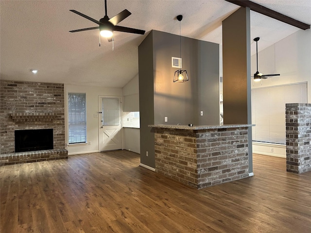 bar featuring a textured ceiling, a brick fireplace, dark hardwood / wood-style floors, lofted ceiling with beams, and ceiling fan