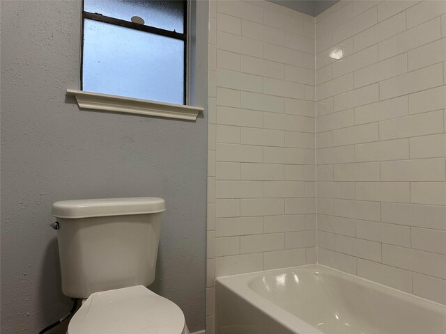 bathroom with toilet and tiled shower / bath combo