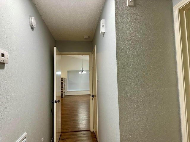 corridor with a textured ceiling and hardwood / wood-style floors