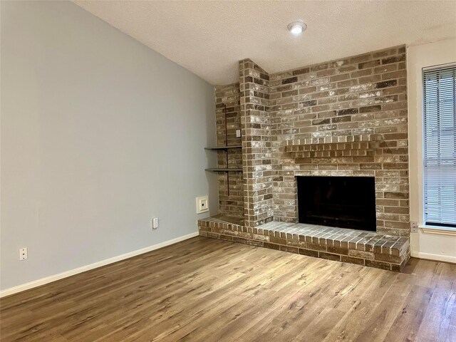 unfurnished living room with a textured ceiling, a fireplace, and wood-type flooring