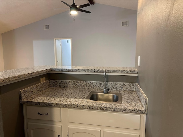 kitchen featuring vaulted ceiling, ceiling fan, white cabinets, and sink