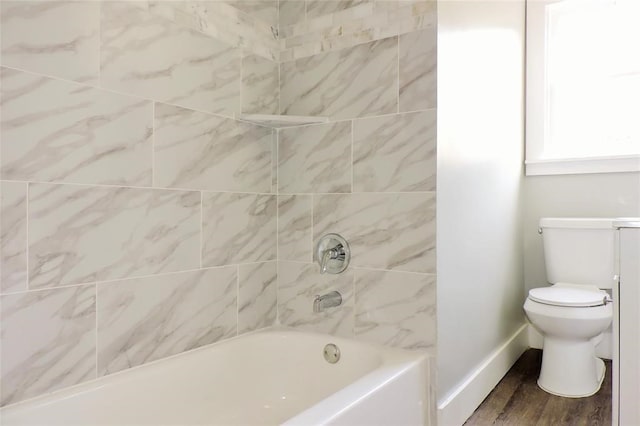 bathroom with toilet, tiled shower / bath combo, and hardwood / wood-style floors